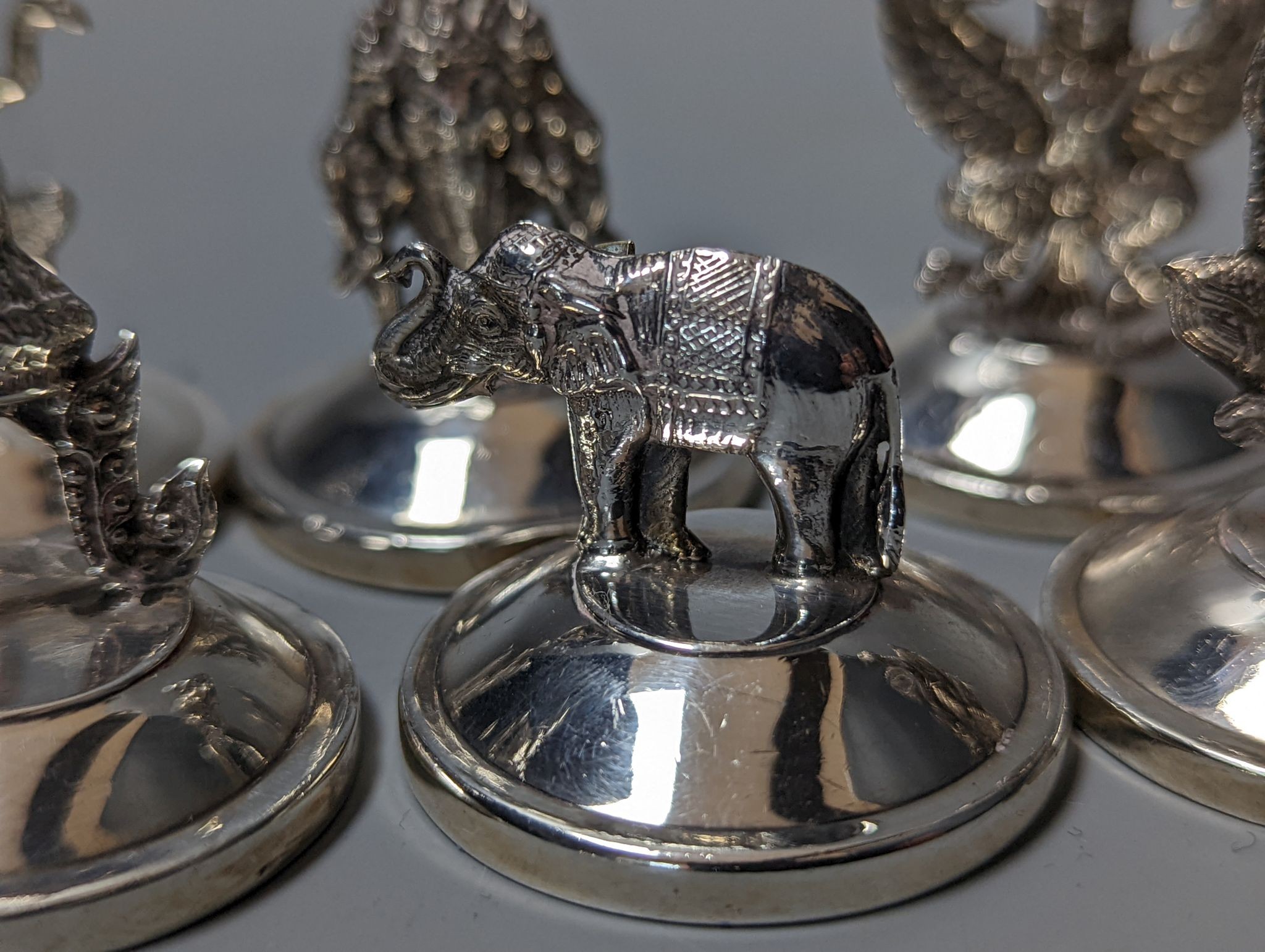 Sixteen assorted Siamese sterling mounted menu holders, modelled with figures, elephant, etc.